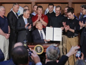 President Donald Trump, accompanied by Environmental Protection Agency (EPA) Administrator Scott Pruitt, third from left, and Vice President Mike Pence, right, is applauded as he hold up the signed Energy Independence Executive Order, Tuesday, March 28, 2017, at EPA headquarters in Washington. (AP Photo/Pablo Martinez Monsivais)